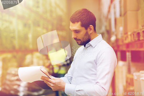 Image of businessman writing to clipboard at warehouse