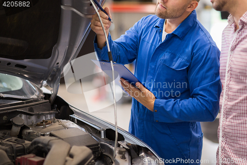 Image of auto mechanic with clipboard and man at car shop