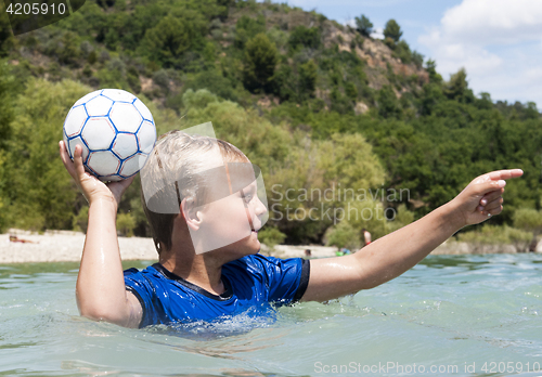 Image of Boy playing in a lake with a ball