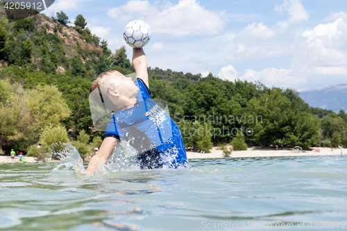 Image of Boy catching a ball in a lake