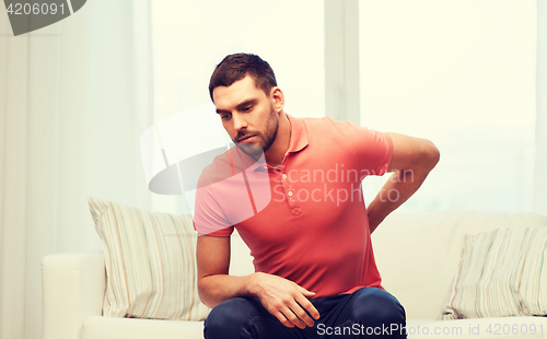 Image of unhappy man suffering from backache at home