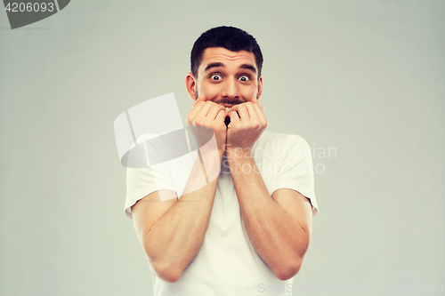 Image of scared man in white t-shirt over gray background