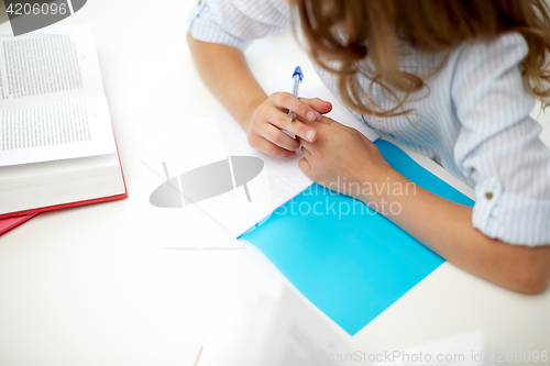 Image of girl with book writing to notebook at school