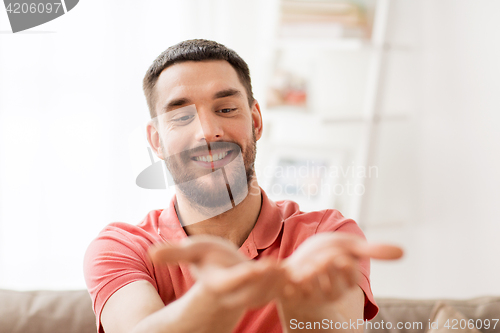 Image of happy man holding something imaginary at home