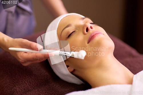 Image of beautician applying facial mask to woman at spa