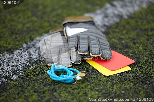 Image of gloves, whistle and caution cards on soccer field