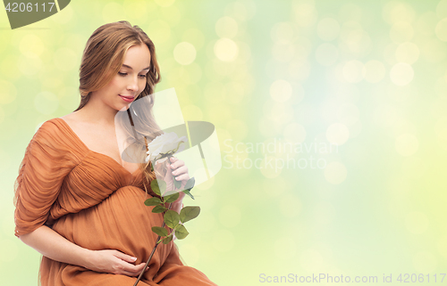 Image of happy pregnant woman with white rose flower