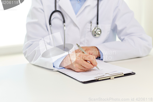 Image of senior doctor with clipboard writing at hospital