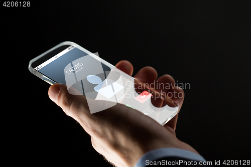 Image of close up of hand with incoming call on smartphone