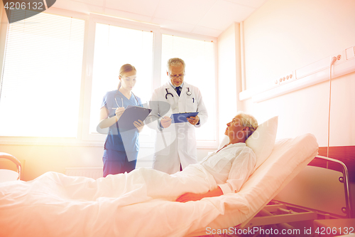 Image of doctor and nurse visiting senior woman at hospital