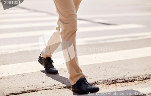 Image of senior man walking along city crosswalk