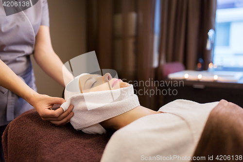 Image of woman having face massage with towel at spa parlor
