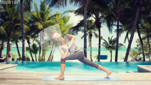 Image of woman making yoga low angle lunge pose over beach