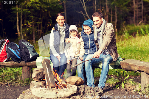 Image of happy family sitting on bench at camp fire