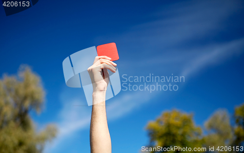 Image of referee hands with red card on football field