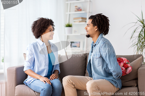 Image of happy couple with bunch of flowers at home