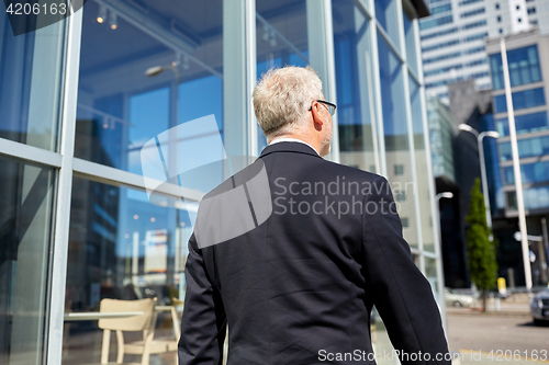 Image of senior businessman walking along city street