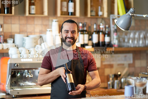 Image of happy man or waiter with bottle of red wine at bar