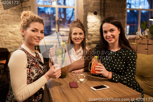 Image of happy friends with drinks at restaurant