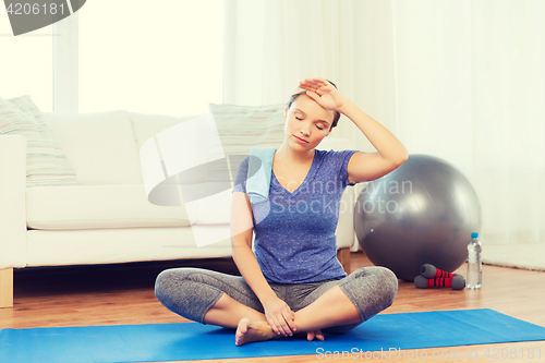 Image of tired woman with towel after workout at home