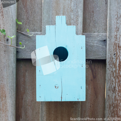 Image of Blue birdhouse on a wooden fence