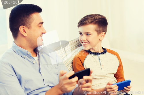 Image of happy father and son with smartphones at home