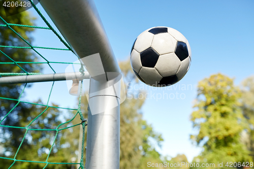 Image of soccer ball flying into football goal net on field