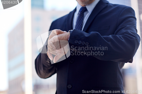 Image of senior businessman with wristwatch on city street