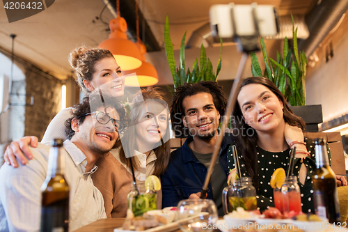 Image of friends taking selfie by smartphone at bar or cafe