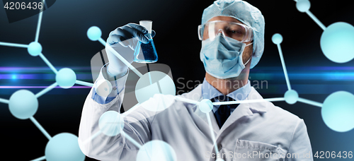 Image of scientist in mask holding flask with chemical