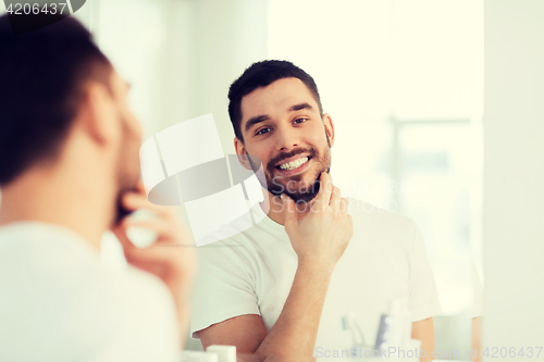 Image of happy young man looking to mirror at home bathroom