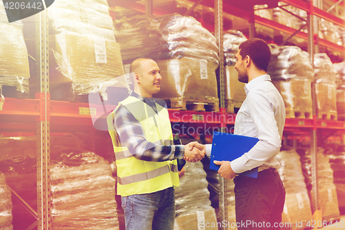 Image of worker and businessmen with clipboard at warehouse