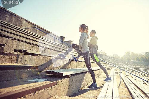 Image of couple stretching leg on stands of stadium