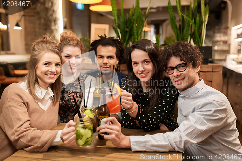 Image of happy friends with drinks at bar or cafe