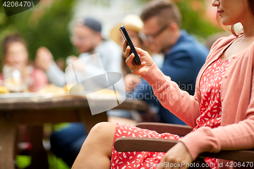 Image of woman with smartphone and friends at summer party