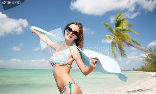 Image of woman in bikini and sunglasses with towel on beach