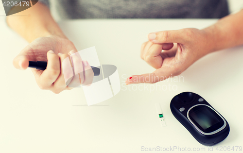 Image of close up of woman making blood test by glucometer