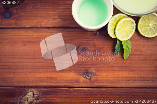 Image of close up of body lotion, cream and limes on wood