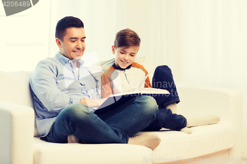 Image of happy father and son reading book at home