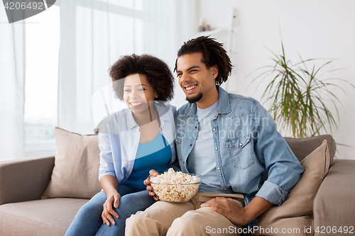 Image of smiling couple with popcorn watching tv at home