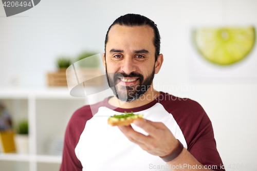 Image of man eating avocado sandwiches at home kitchen