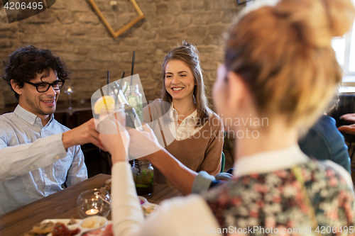 Image of happy friends clinking drinks at bar or cafe