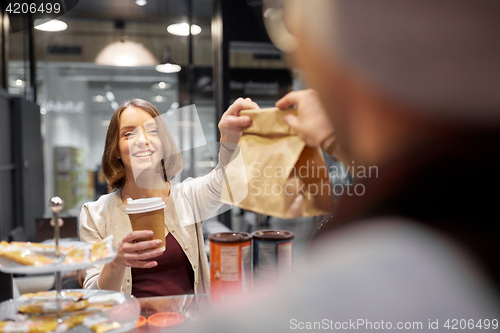 Image of woman taking paper bag from seller at cafe