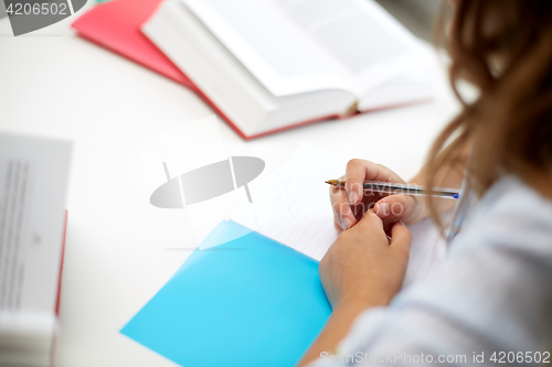 Image of girl with book writing to notebook at school