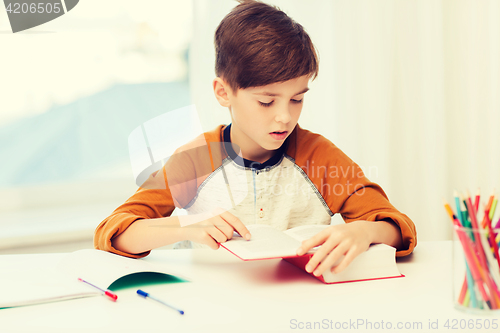 Image of student boy reading book or textbook at home