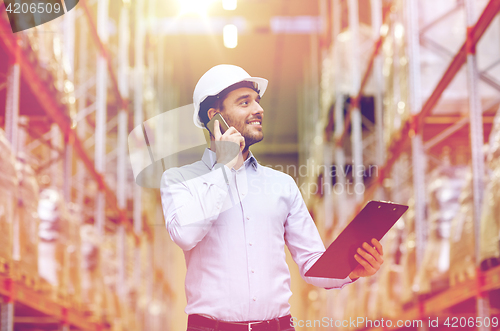 Image of man with clipboard and smartphone at warehouse