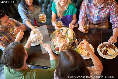 Image of happy friends eating and drinking at bar or pub