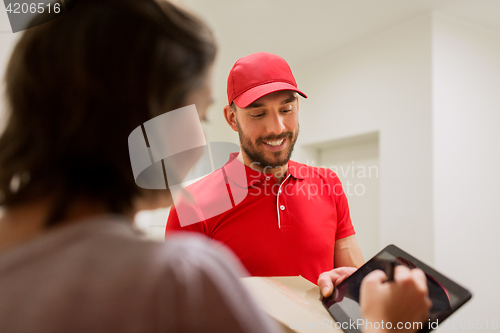 Image of delivery man with box and tablet pc at customer