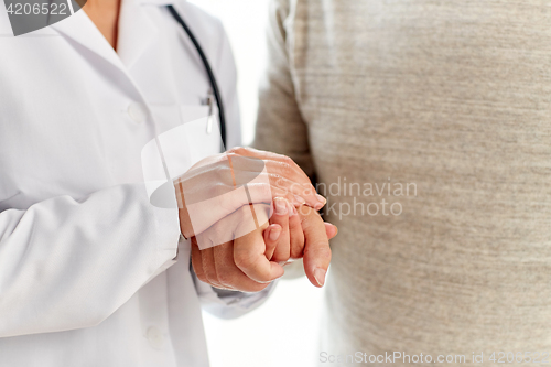Image of close up of doctor holding old man hand