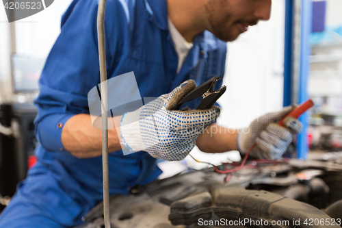 Image of auto mechanic man with cleats charging battery